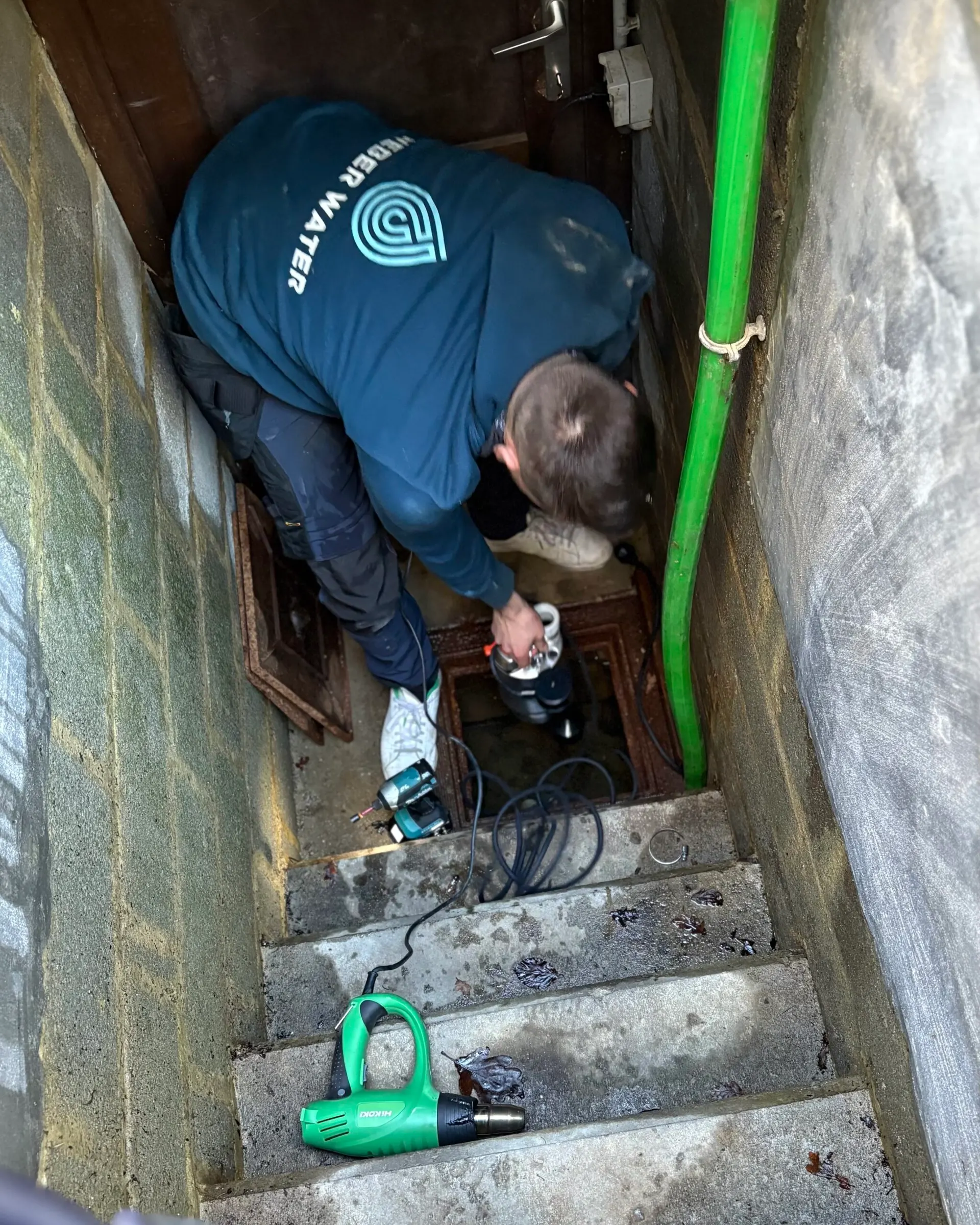 Technicien Weber Water posant une pompe dans une cage d’escalier de cave